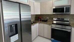 Una cocina moderna con electrodomésticos de acero inoxidable, microondas integrado y cafetera.