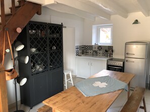 Una cocina con una mesa de madera, un armario negro y una encimera blanca.
