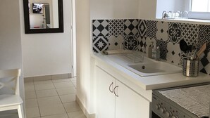 Une cuisine avec des meubles blancs, un pare-feu en carrelage, un évier et un four.