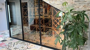 A modern interior with a glass door leading to a wine cellar, a patterned floor, and a stone wall. - Villa with spa pool petanque court (Narbonne)