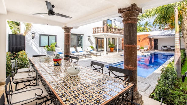 Un'ampia area esterna con piscina, tavolo da pranzo con sedie e zona relax con poltrone.