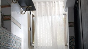 A bathroom with patterned tiles, a white shower curtain, and a black door. - A charming house in the heart of La Marsa. (La marsa)