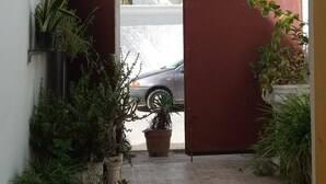 A narrow courtyard with a red gate, potted plants, and a parked car. - A charming house in the heart of La Marsa. (La marsa)