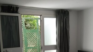 A bedroom with a bed, a sliding glass door leading to a garden, and a dark headboard. - A charming house in the heart of La Marsa. (La marsa)