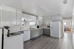 Une cuisine moderne avec des meubles blancs, un lave-vaisselle, un four à micro-ondes et un réfrigérateur.