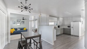 A modern kitchen with white cabinets, a central island, and a dining area with a wooden table and bar stools.
