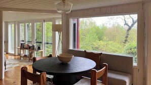 Een eetgedeelte met een ronde tafel, stoelen, een schaal en een bank.