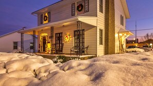 Una casa a due piani con un portico, decorata con corone e luci natalizie.