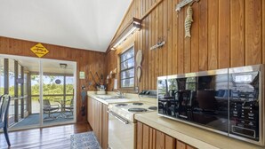 A wooden interior with a kitchen featuring a Samsung microwave, a stove, and a sink. There is a redfish crossing sign on the wall and a wooden sign above the stove.