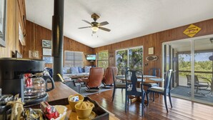 A cozy cabin interior with a wooden interior, a large window, and a dining area with chairs and a table.