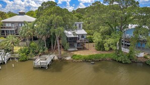 A lakeside property with a dock, a house with a large deck, and surrounding lush greenery.