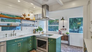 A spacious kitchen with green cabinets, a large island, and a brick floor. - Ferry Cove - Private low bank beachfront property. (Clinton)
