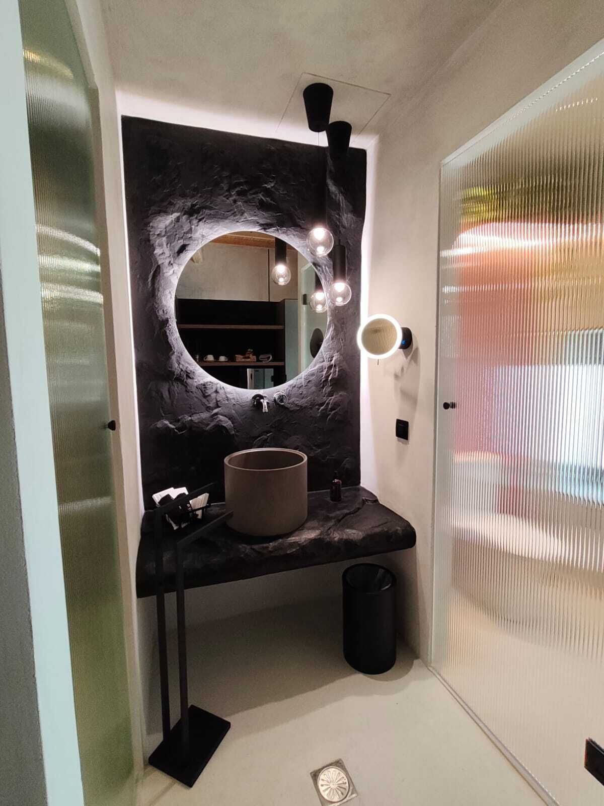 Un baño con un espejo redondo, un lavabo y un mueble de tocador.