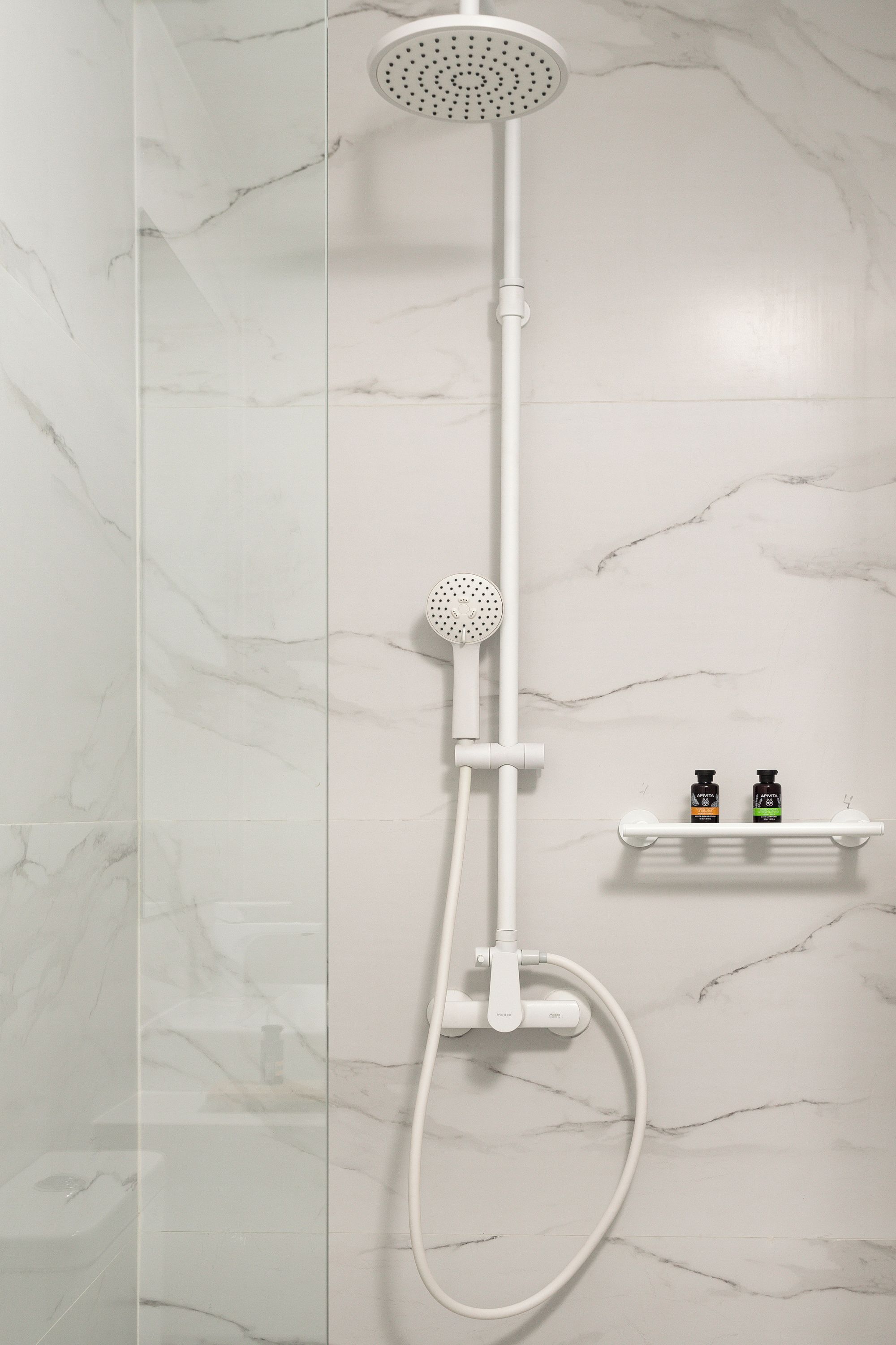Une douche moderne dotée d’un pommeau de douche à main et d’un panneau de commande fixé au mur.