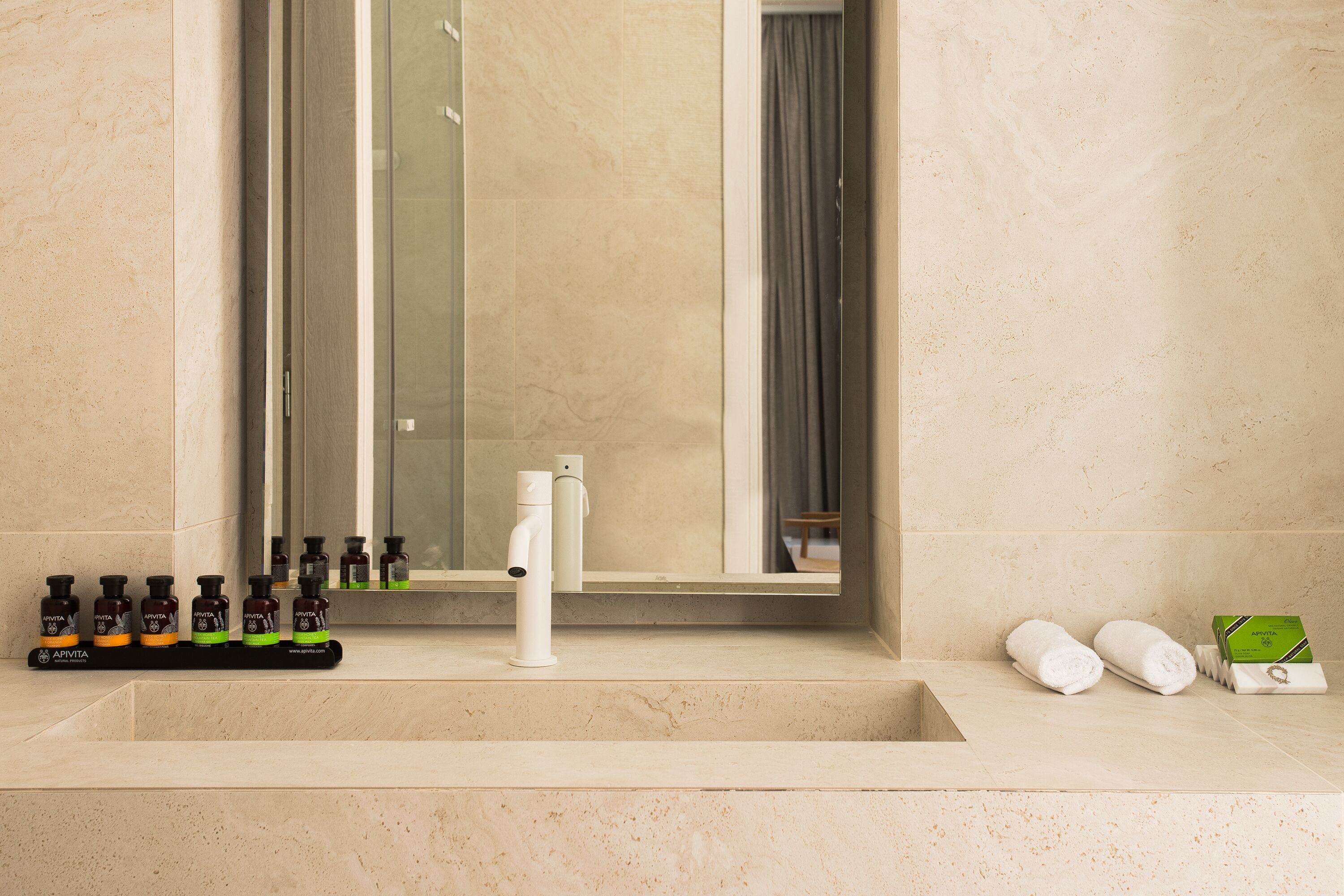 Une salle de bain avec un lavabo en marbre, un miroir et des articles de toilette.