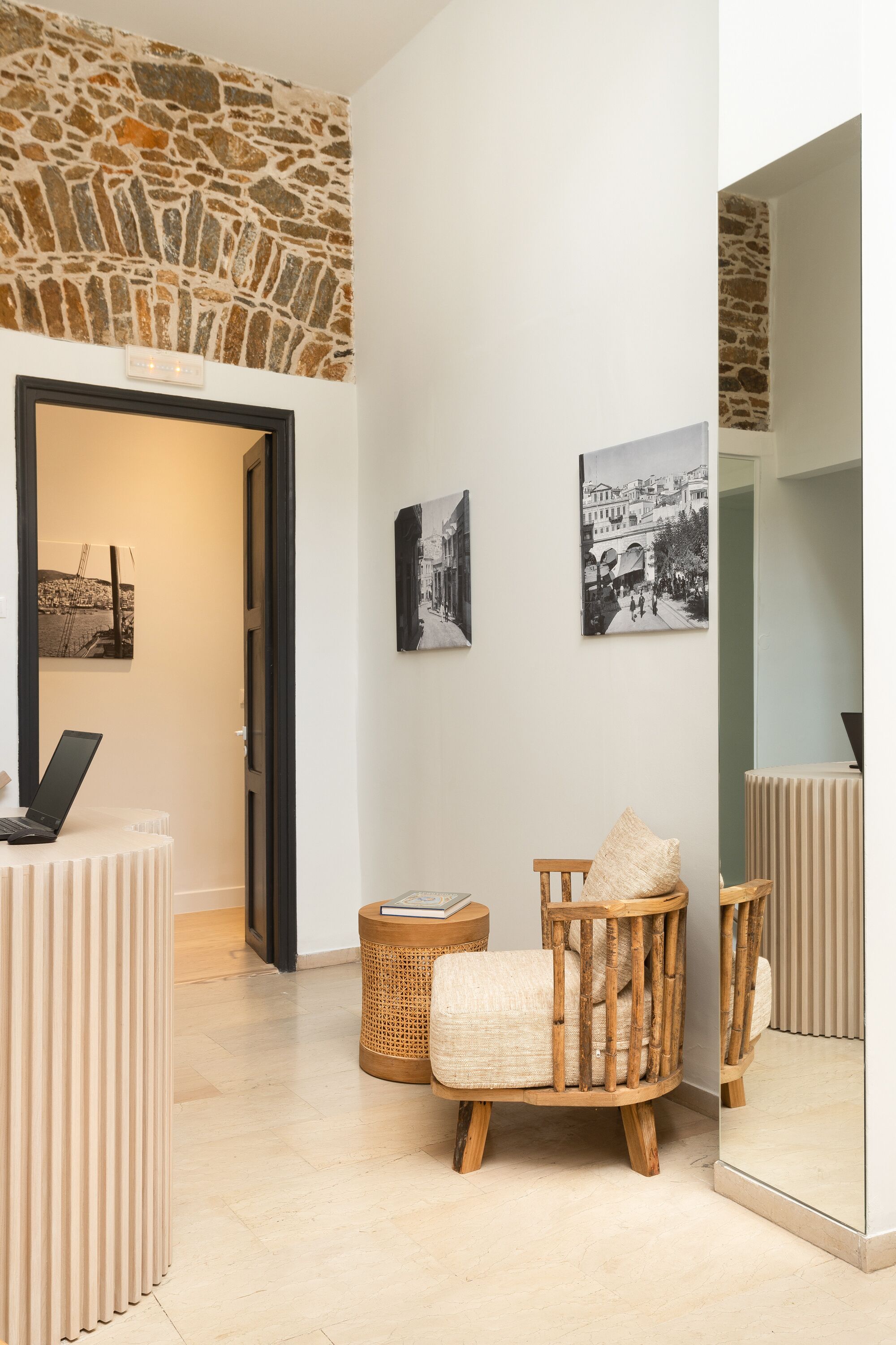Een modern interieur met een stenen muur, een houten stoel, een rieten mand en een laptop op een tafel.