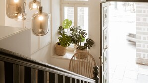 Una escalera con barandilla de madera, una planta en maceta y lámparas colgantes.
