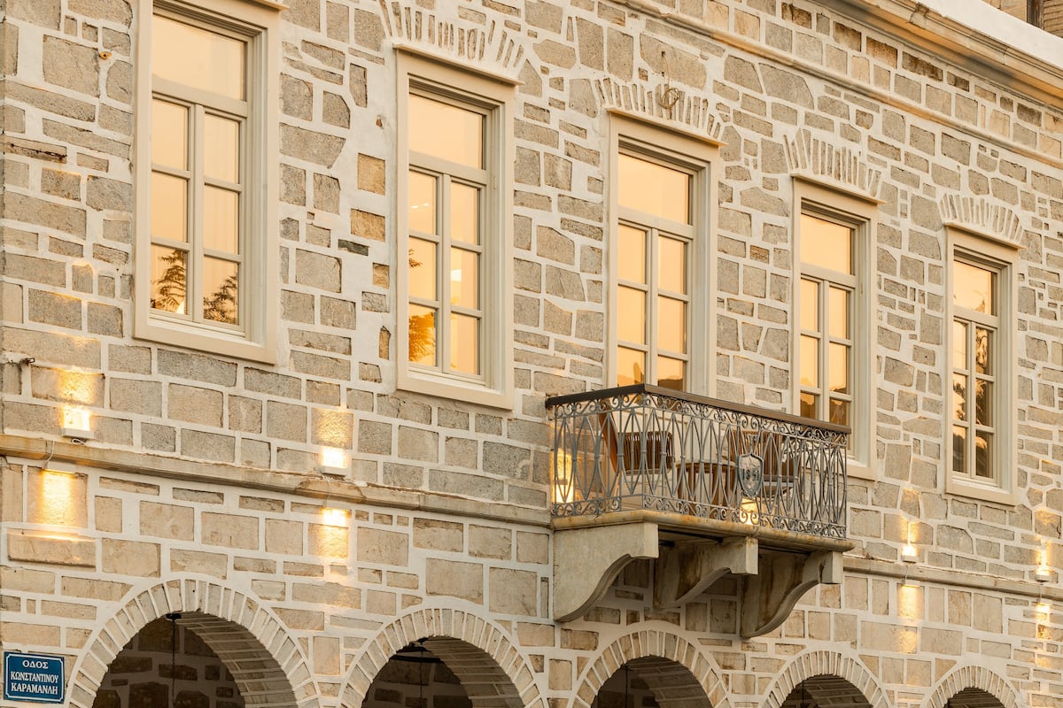A stone building with arched windows and a balcony with wrought iron railings.