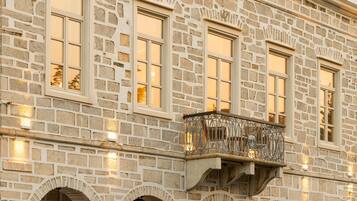 A stone building with arched windows and a balcony with wrought iron railings.