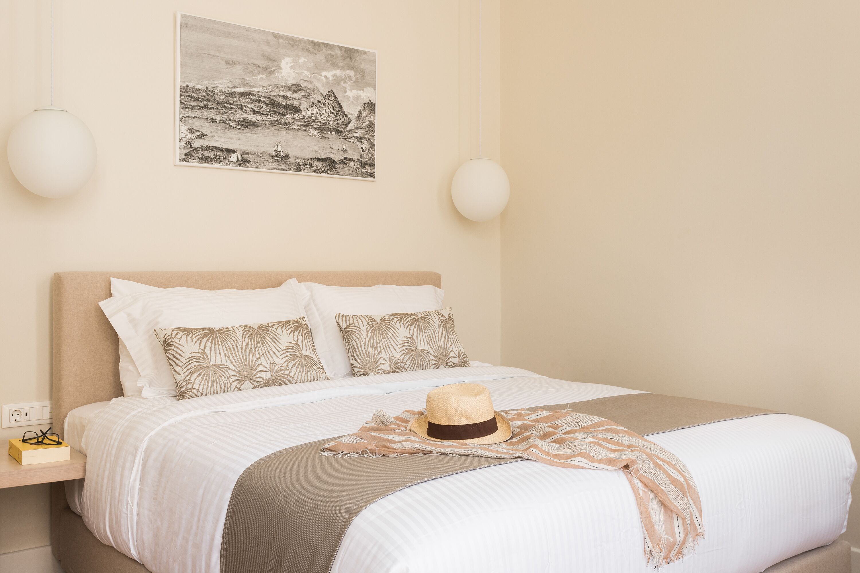 Una cama bien hecha con un sombrero, almohadas y una manta.