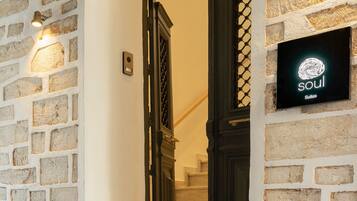 A stone wall with a sign reading "soul Suites" above a set of marble stairs leading to a dark wooden door.