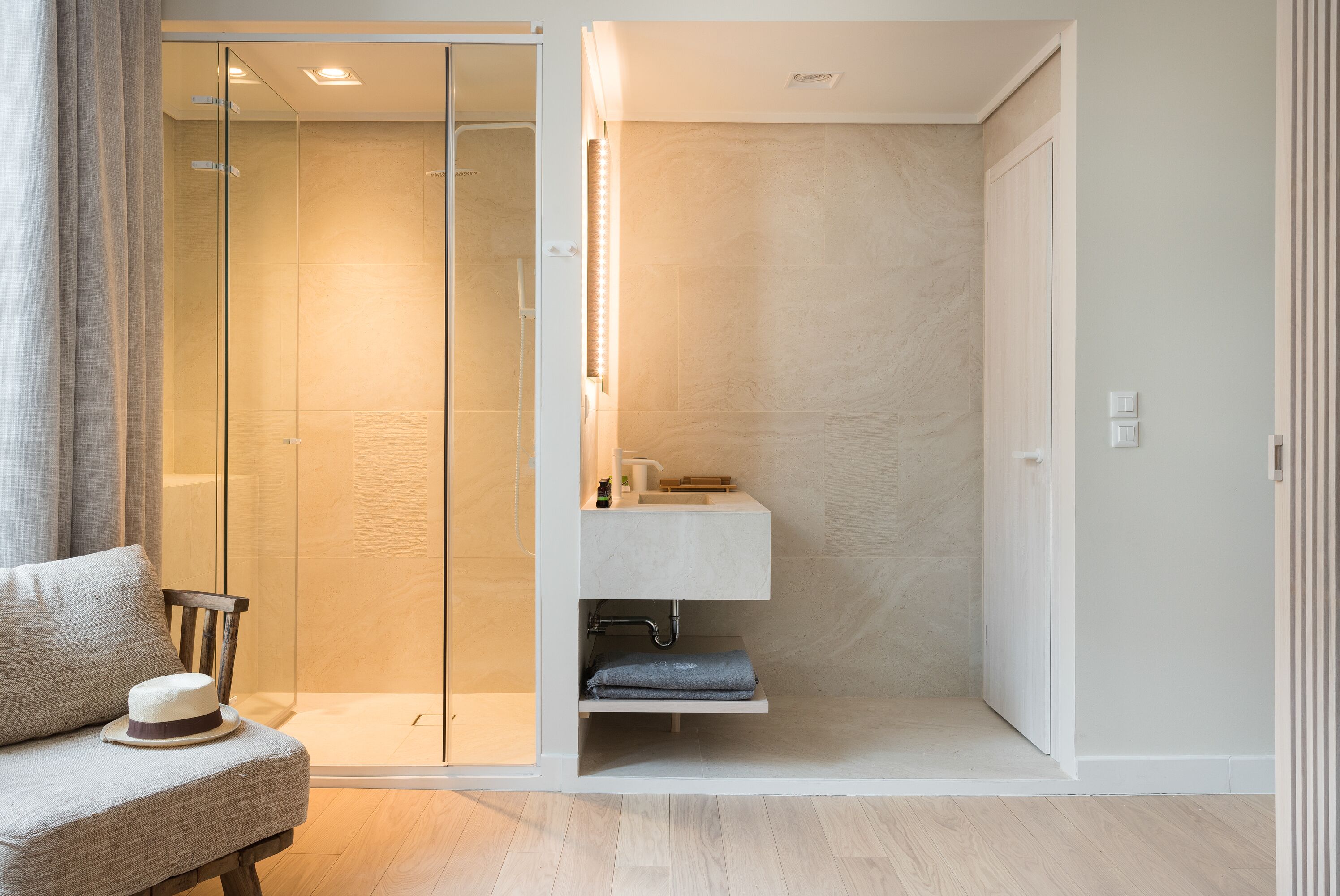 A modern bathroom with a glass shower enclosure, a built-in sink, and a towel rack.