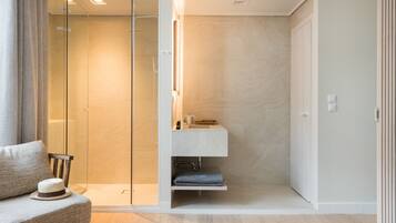 A modern bathroom with a glass shower enclosure, a built-in sink, and a towel rack.
