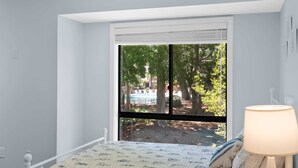 Ein Schlafzimmer mit einem Bett, einem Fenster mit Jalousien und einer Lampe.