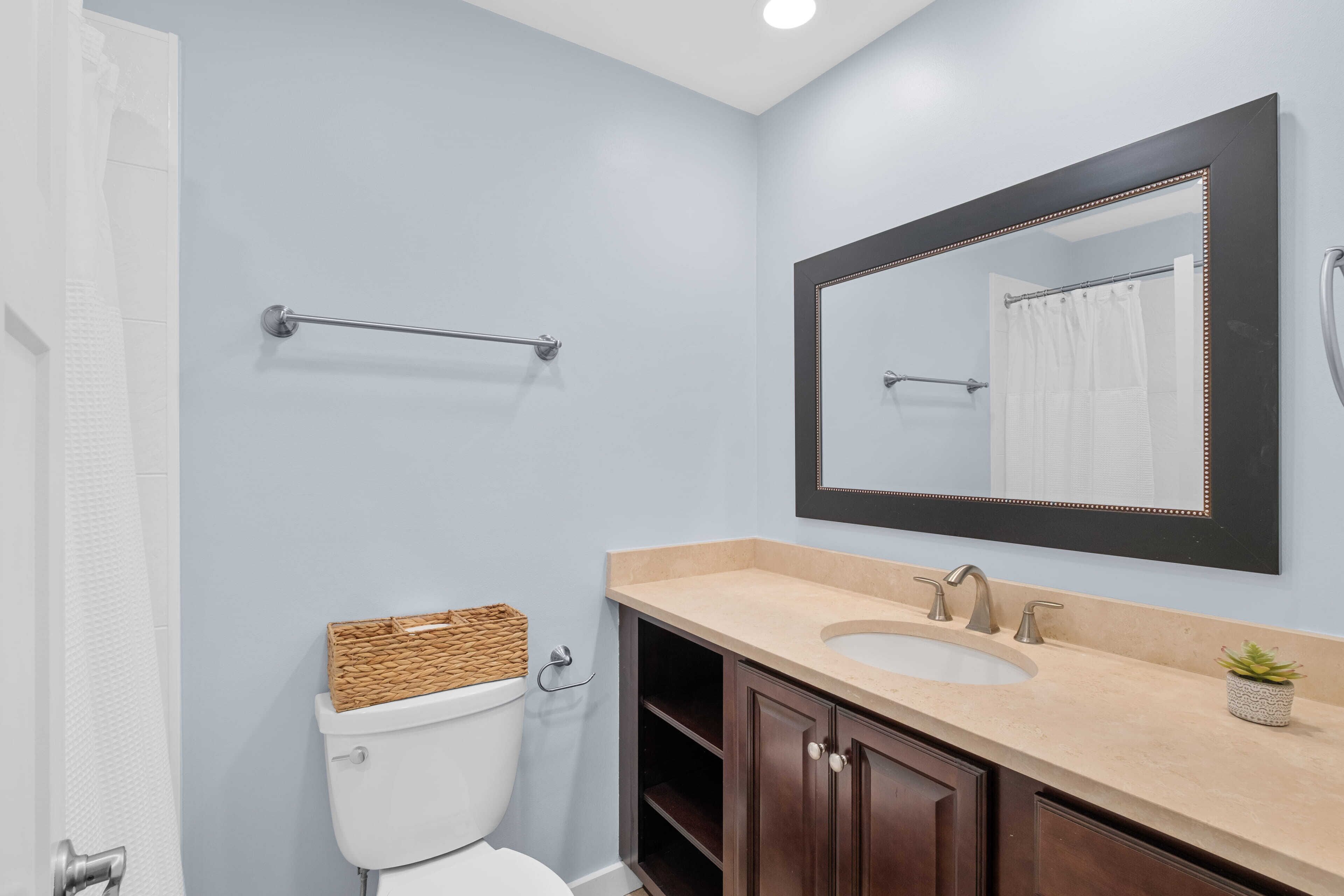 A bathroom with a toilet, a sink, a mirror, and a towel rack.
