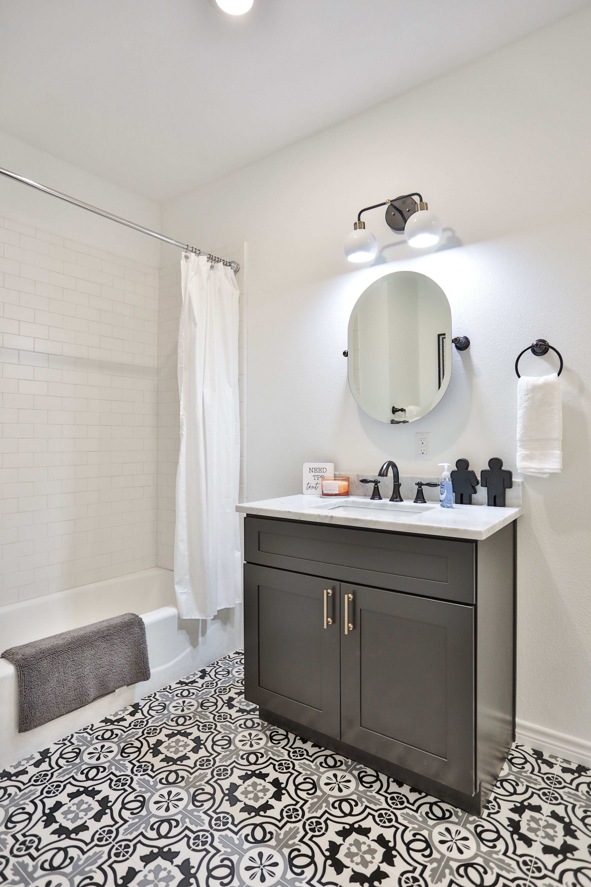 A bathroom with a bathtub, a vanity with a mirror, and a shower curtain.