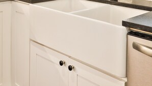 Une cuisine avec des armoires blanches, un évier en acier inoxydable et un miroir décoratif au-dessus de l’évier.