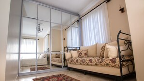 Ein Zimmer mit einem Spiegelkleiderschrank, einer Couch, einem gemusterten Teppich und einem Bett.