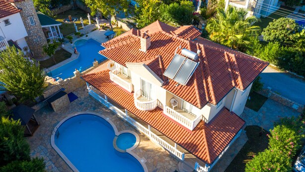 Ein Haus mit Pool, überdachter Terrasse und rotem Ziegeldach.
