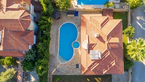 Eine Vogelperspektive eines Wohnhauses mit Swimmingpool, Kiesweg und roten Ziegeldächern.
