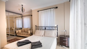Ein Schlafzimmer mit einem Bett, einem Schminktisch, einem Spiegel, einer Chandelier und einem Sofa.