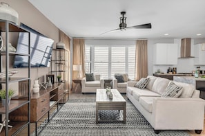 A modern living room with a sofa, coffee table, and a TV on a wall.