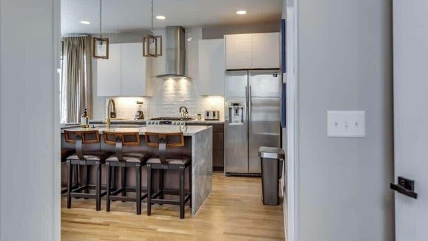 A modern kitchen with a central island, bar stools, stainless steel appliances, and pendant lighting. - Charming Rustic Stay – Near Belmont (Nashville)