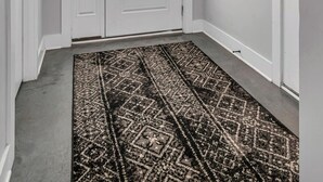 A hallway with a patterned rug, a double door, and a framed poster on the wall. - Charming Rustic Stay – Near Belmont (Nashville)
