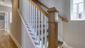 A staircase with white railings and a wooden handrail, leading to an upper floor. - Charming Rustic Stay – Near Belmont (Nashville)