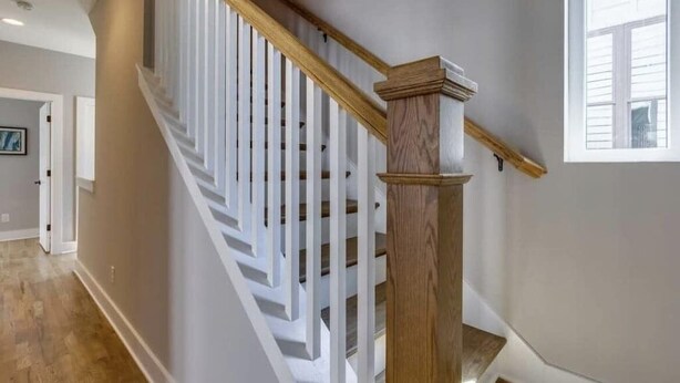 A staircase with white railings and a wooden handrail, leading to an upper floor.