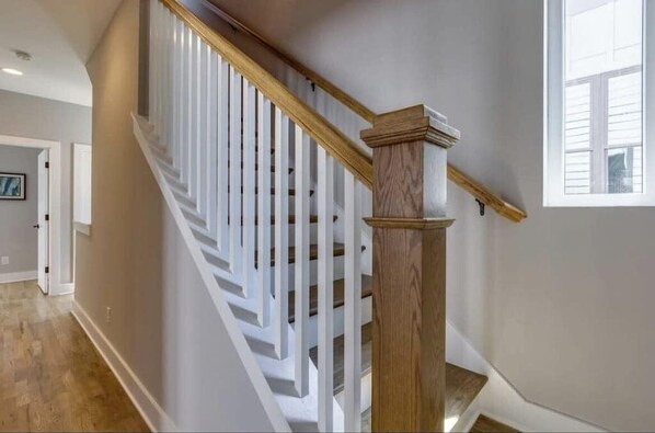 Eine Treppe mit weißen Geländern und einem Holzhandlauf, die zu einer oberen Etage führt.