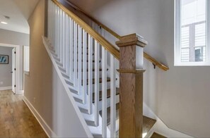 A staircase with white railings and a wooden handrail, leading to an upper floor.