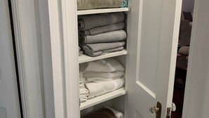 Un armario blanco con repisas que contienen toallas dobladas en varios colores.