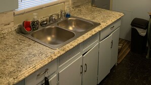 Una cocina con encimeras de granito, pileta doble y muebles blancos.