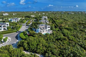 A residential area with modern houses, a winding road, and dense greenery. - Modern Villa Steps to Long Bay Beach w/ Pool (Long Bay)