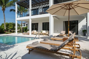 Ein modernes Resort mit Pool, Liegestühlen und einem überdachten Außenbereich.