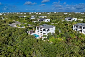 A residential area with modern houses, a swimming pool, and lush greenery.