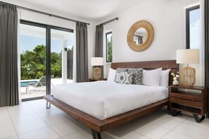 Ein modernes Hotelzimmer mit einem großen Bett, einem runden Spiegel und Blick ins Freie.