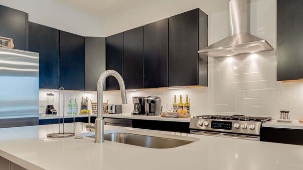 A modern kitchen with a stainless steel sink, a gas stove, and black cabinets.