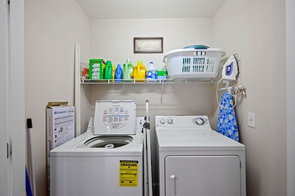 A laundry room with a washing machine, dryer, and shelves holding cleaning supplies. - CLOSE to the heart of Pigeon Forge w/flat,EZ parking, near the river & free Wifi (Pigeon Forge)